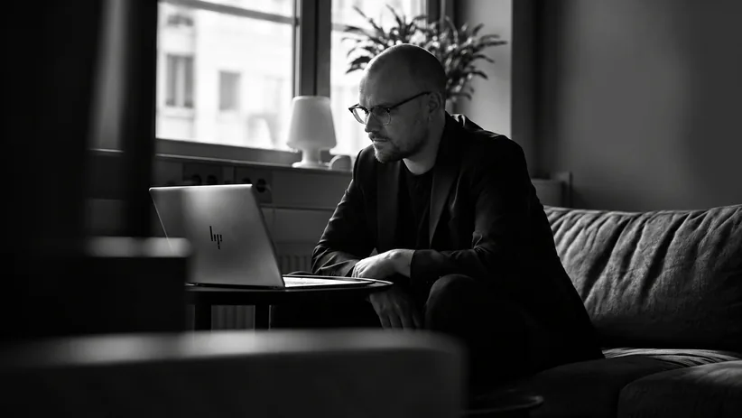 Man som arbetar vid en laptop i en soffa